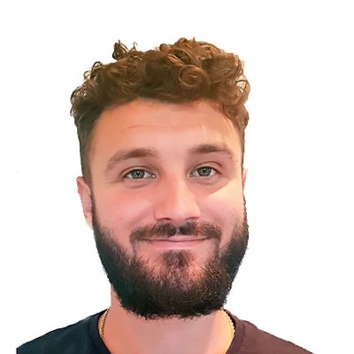 Smiling man with curly hair and beard against a white background.