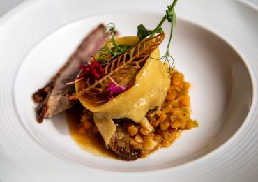 Gourmet dish with meat, beans, and edible garnish.