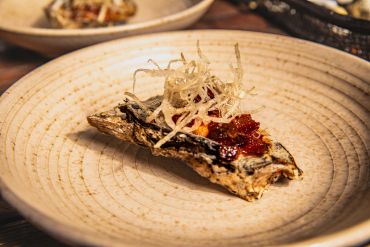 Gourmet dish with grilled fish and garnish on a beige plate.
