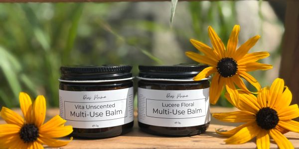 Two multi-use balm jars with yellow flowers in natural light.