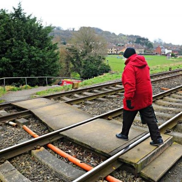 Person in red jacket crossing railroad tracks.