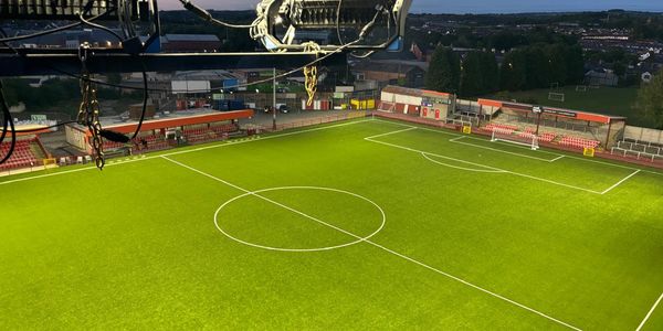 Empty football stadium illuminated at dusk with clear field markings.