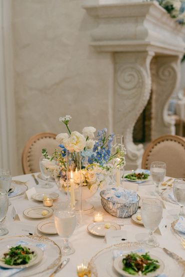 Elegant wedding table setup with floral centerpiece and lit candles.