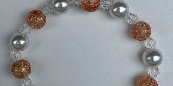 A beaded bracelet with alternating silver and amber-colored beads.