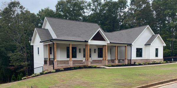 Modern white house with wooden pillars and a fresh lawn on a sloped street.