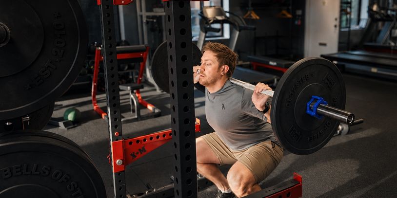 Client performing a barbell squat at LiV studio.