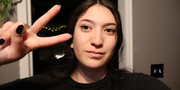 Young woman showing peace sign indoors at night.