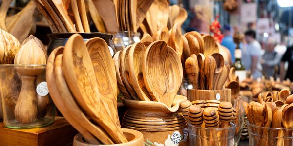 A collection of handcrafted wooden spoons and kitchen utensils displayed for sale.