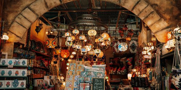 Colorful lanterns and decorative items light up a cozy market stall under an arched entrance.