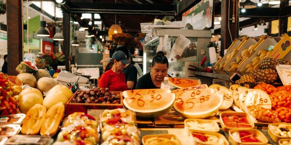 Vendors selling fresh fruits and vegetables at a vibrant market stall.