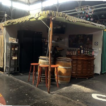 Cozy indoor bar setup with barrels as tables and stools under a striped canopy.