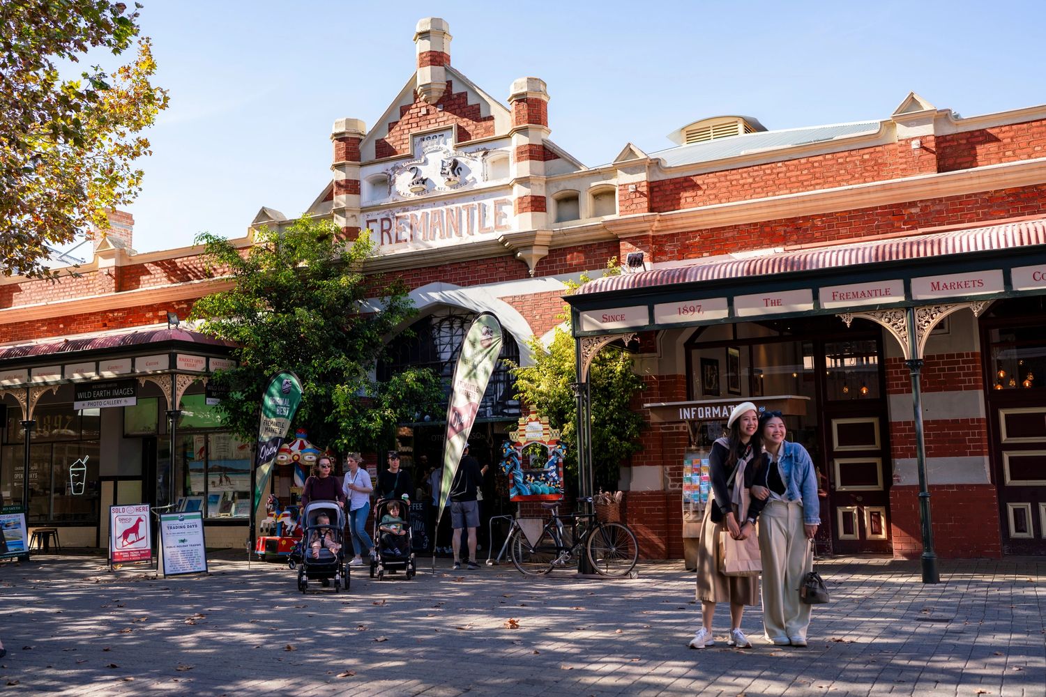 Two women posing happily outside the historic Fremantle Markets building.