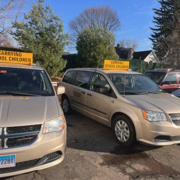 Two beige vans with 'Carrying School Children' signs.