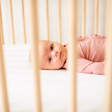 Baby girl laying in crib, sleep training baby in crib, sleep consultant supporting family with crib 