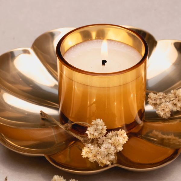 Lit candle in a golden holder with dried flowers.