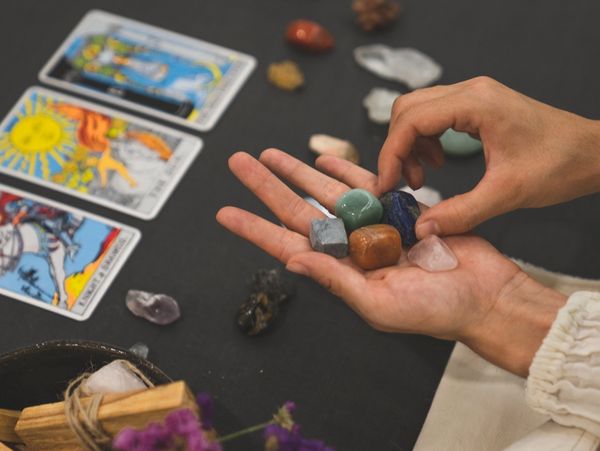Healing crystals and tarot cards in hand.