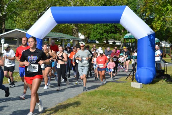 Runners participating in a community race under a blue and white inflatable arch.
