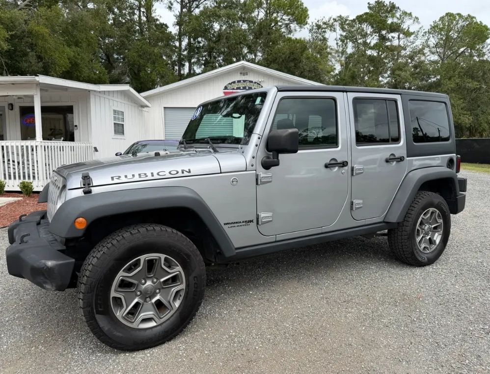 Silver Jeep Wrangler Rubicon parked outside a white building.