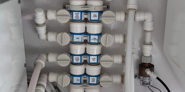 Close-up of a complex plumbing manifold with labeled valves and pipes.