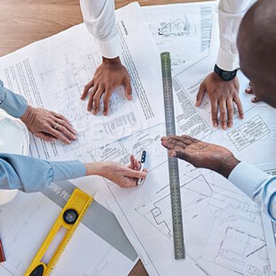 Team collaborating over architectural blueprints and tools.