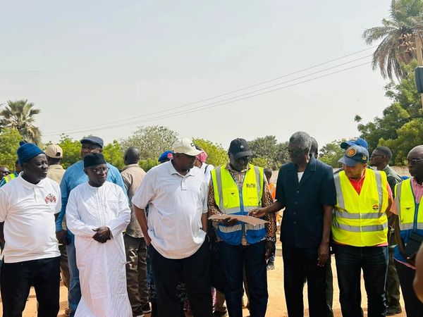 Group of men in casual and traditional attire discussing outdoors.