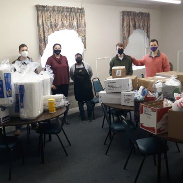 Group of people with donation boxes in a room.