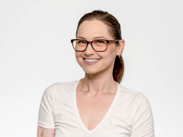 Smiling woman with glasses and white shirt.
