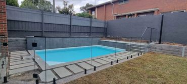 Frameless glass pool fence fitted on black spigots with black nanorail