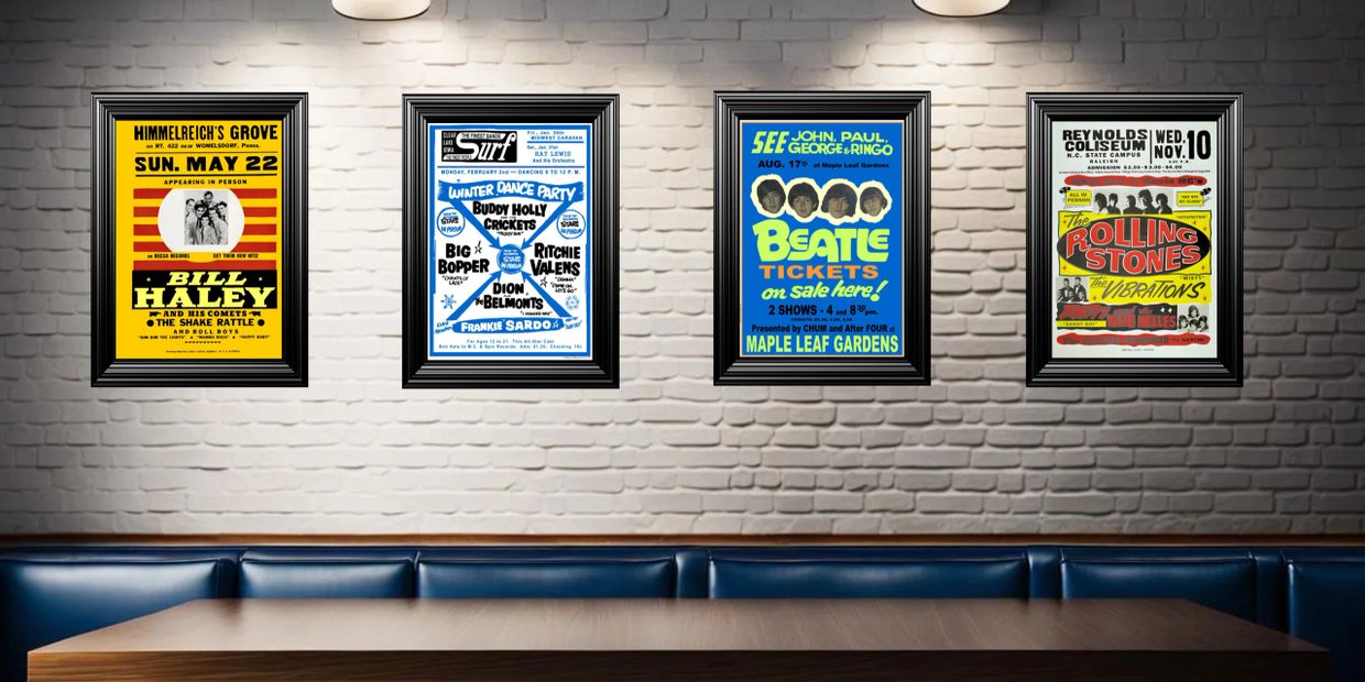 Framed vintage concert posters of Bill Haley, Buddy Holly, The Beatles, and The Rolling Stones on a white brick wall.