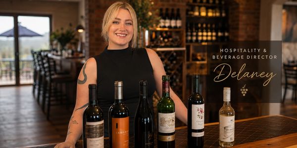 Hospitality and Beverage Director Delaney showcasing various wine bottles in a stylish setting.