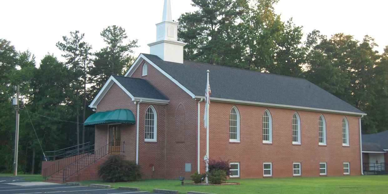 A brick church building with a white steeple.