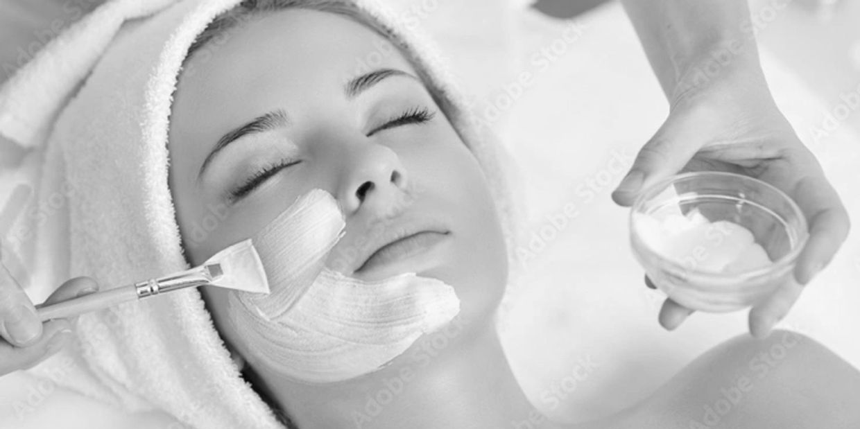 Woman receiving a facial treatment with a creamy mask being applied.
