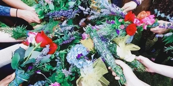 bunch of people holding flowers and plants in a circle 