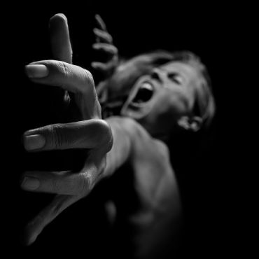 Black and white photo of a person reaching out with intense emotion.
