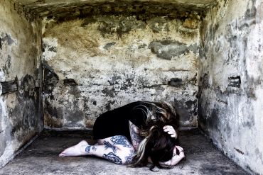 Person curled up in a worn, enclosed space.
