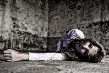 Person lying on the floor in a distressed state.