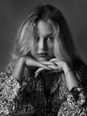 Black and white portrait of a woman with intense gaze and patterned shirt.