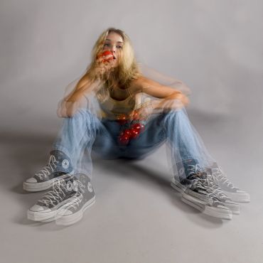 Blurred double exposure of a person sitting, holding cherries.