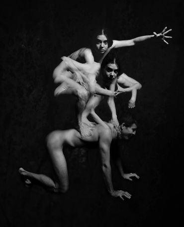 Three dancers intricately posed in a surreal, artistic black and white composition.