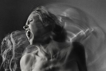 Black and white photo showing a woman screaming with a blurred motion effect.