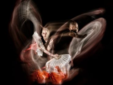 Artistic image of a dancer with motion blur and fans creating dynamic swirls.