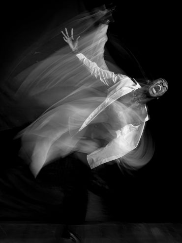 Black and white image of a person in motion, expressing intense emotion.