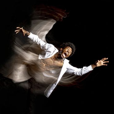 Man in white shirt with blurred motion effect on black background.