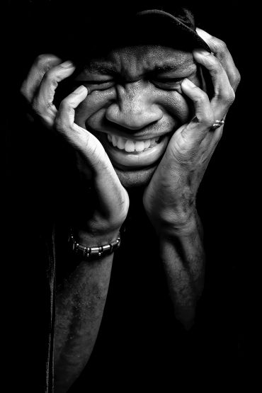 Black and white portrait of a person tightly holding their face in emotional intensity.