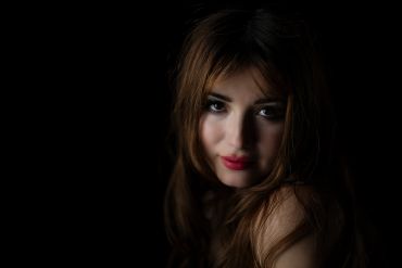 Portrait of a woman with soft lighting and dark background.