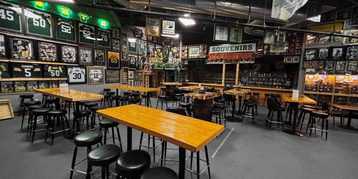 Sports-themed bar with Green Bay Packers memorabilia and wooden tables.