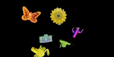 Colorful embroidered patches of butterfly, sunflower, camera, scorpion, cactus, and gun on black background.