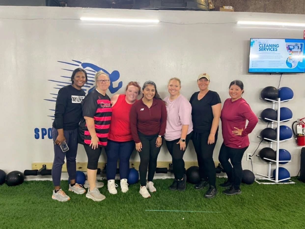 Group of women posing in a gym setting.