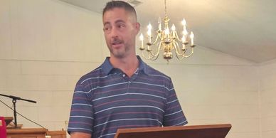 Man speaking at a podium with chandelier overhead.