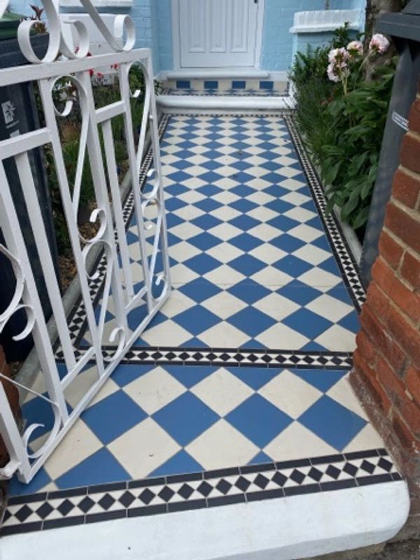 Checkerboard tiled pathway leading to a blue door with white gate.